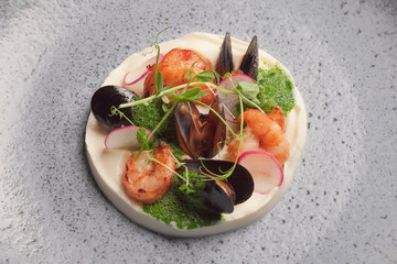 Restaurant menu. Mashed potatoes with seafood. Oysters and prawns with radish sauce and microgreens. Blue plate. Ceramic ware.
