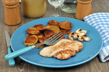 Veal cutlet with fried potatoes served in a plate