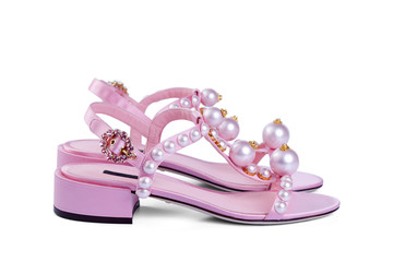 Pair of women's open satin pink shoes with large pearls and a brooch clasp, isolated on a white background with a light shadow. Side view.