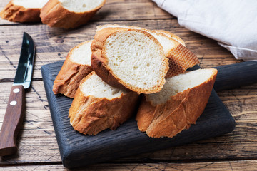 Fresh white bread baguette cut slays on a wooden cutting Board.