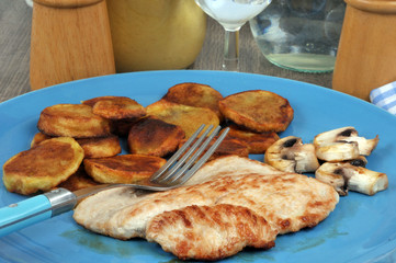 Veal cutlet with fried potatoes served in a plate