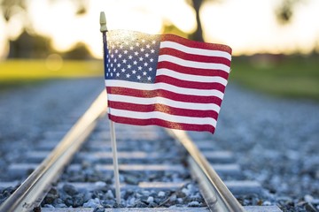 Closeup shot of the flag of the USA on the train rails covered by the sunlight