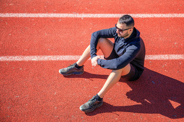 Athletes walk and stretch on the red wet track of athletics, which is a rubber artificial track for run and field athletes.