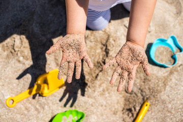 Close up hands of happy girl playing in sand.