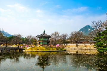 Fototapeta na wymiar Hyangwonjeong Pavilion on an artificial island of Hyangwonji lake under bright blue sky with Mount Bugak as backdrop on springtime. It's location is in Gyeongbokgung Palace.