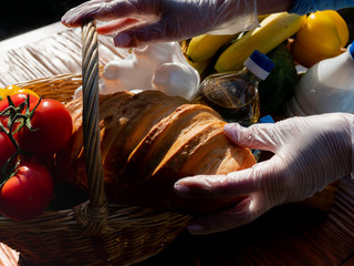 Woman in protective medical gloves creates food parcels for patients in isolation.