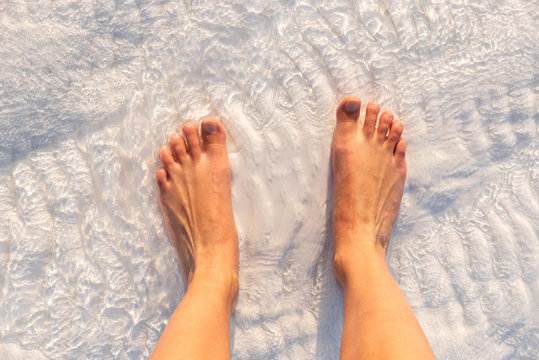 Barefoot standing over white limestone textured with water in Pamukkale, Turkey