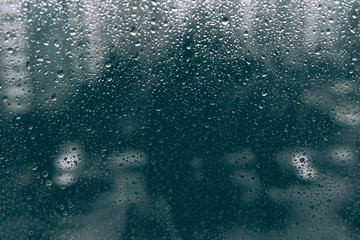 rainy droplets on a dark black window glass. wet drops on window shield in a rainy days in night city. stormy weather. sad depression concept. rainy season.