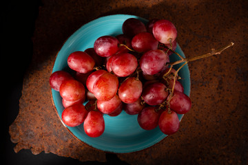 Table grape cluster in ceramic bowl on brown background