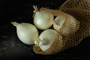 Sack with onions, on black background