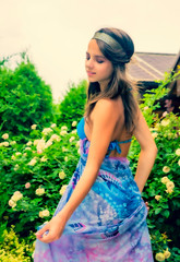 Beautiful young woman posing against a backdrop of greenery and a bungalow with a blue tissue. Elegant girl with scarf and bijouterie enjoying at beach. Freedom and carefree concept, Bali. tanning