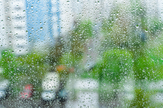 rainy droplets on a window glass. transparent surface. drops on window shield in a rainy days  in a city. stormy weather.  rainy season. stay home.