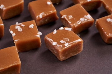 Pieces of salted caramel on dark paper background