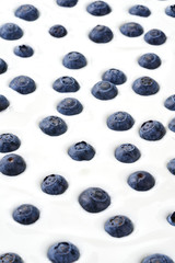 Vertical shot of blueberries dropped in yoghurt 
