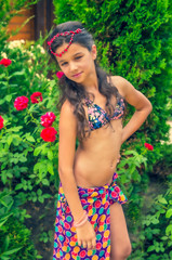 cute fashion little child girl in a vibrant swimsuit and leek posing on a backdrop of a garden. summer time. Fashionable summer glamor concept.