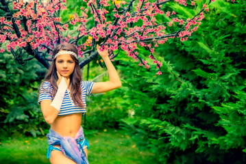 beautiful brunette girl in short striped blue and white shirt, swimsuit and pore on the street in the Park. Fashionable summer glamor concept. Summer walk. Copy space