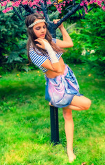 beautiful brunette girl in short striped blue and white shirt, swimsuit and pore on the street in the Park. Fashionable summer glamor concept. Summer walk.