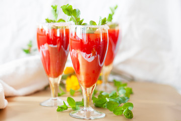 Glasses of homemade cold juice with mint with fresh berries on a light background. Selective focus.