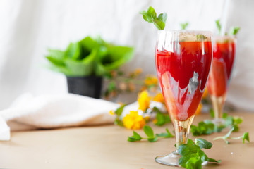 Crystal bakery with a drink, homemade cold juice with mint with fresh berries on a light background. Selective focus.