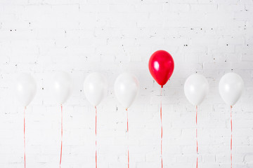 Unique red balloon among another on white background