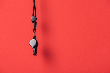 Black whistle with rope on red background
