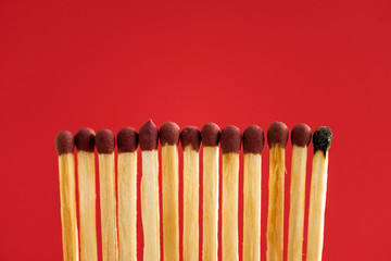 Burned match among another isolated on red