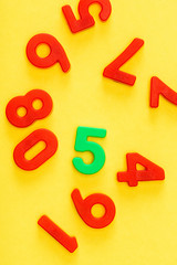 Top view of unique green five number among red on yellow
