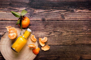 Bottle of tangerine juice and fresh fruit on a wooden background. Healthy life concept.
