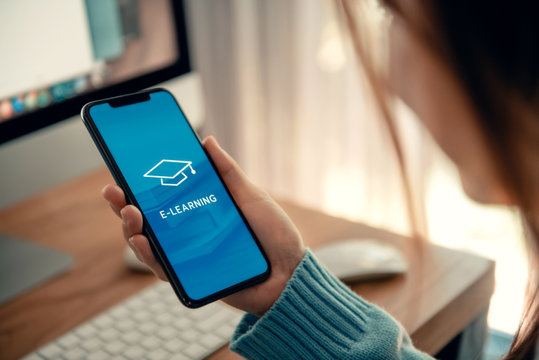 Online education, e-learning. Young woman using mobile phone with inscription on screen e-learning and image of square academic cap, distance training.