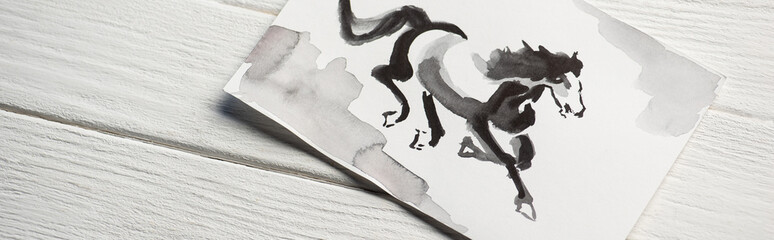 Top view of paper with japanese painting with horse on wooden background, panoramic shot