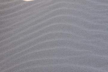Obraz premium The pattern of waves in a grey sandy beach.