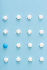 Flat lay with unique pill among white on blue background