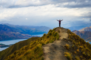 Woman standing on top of a mountain, view of lakes. Roy's Peak, Wanaka, New Zeland