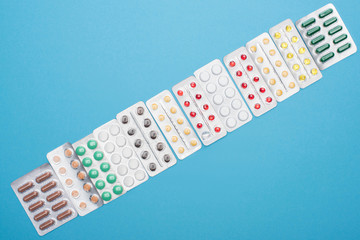 top view of colorful pills in blister packs on blue background