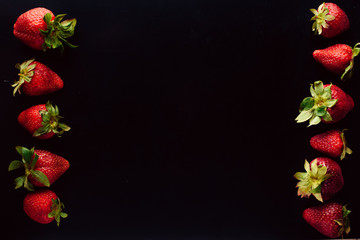 Fruit frame with strawberries on a black background. Free space in the center. Top view