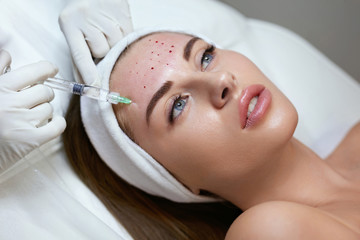 Face Treatment. Anti Aging Beauty Injection In Forehead. Skincare Rejuvenation Procedure In Cosmetic Clinic. Beautician Hands In Gloves With Syringe.