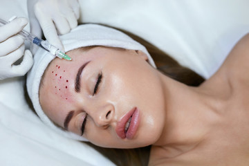 Obraz na płótnie Canvas Face Beauty Treatment. Woman Receives Anti Aging Injection In Forehead. Cosmetology Skincare Thepary In Medical Clinic.