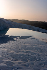 Calm pond in white limestone mountains in Pamukkale, Turkey on a sunny day