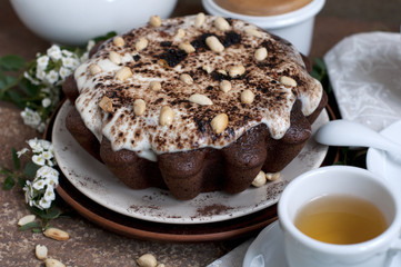 Chocolate cake with peanuts on table with tea and flowers