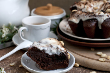 Chocolate cake with peanuts on table with tea and flowers