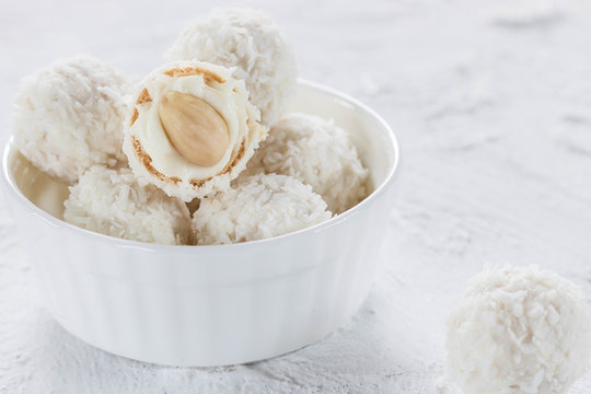 Candies with nougat and almonds in coconut flakes on a light background