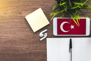 learning Turkish, a smartphone with a Turkish flag and a notebook for writing foreign words on a...