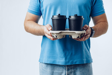 Man coffee shop worker giving takeaway cups of coffee on light grey background