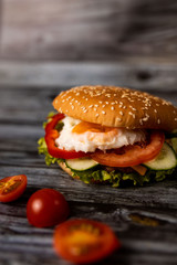 Burger with vegetables and egg on the wooden background