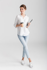 Image of joyful woman drinking coffee takeaway and holding laptop