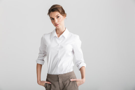Image of young beautiful woman posing with hands in pockets