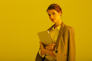 Image of serious pretty woman posing with laptop on camera