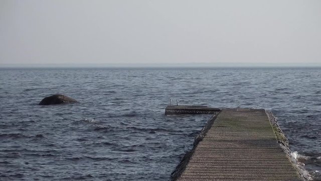 Wooden pier in the sea or lake. Calm and small waves.