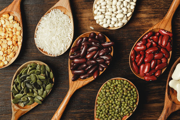 dried beans in wooden spoons on the table, close up
