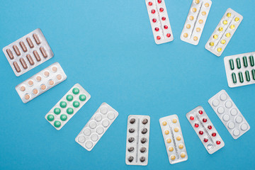 top view of colorful pills in blister packs on blue background